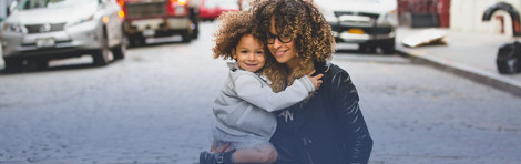 woman holding her daughter standing in the street